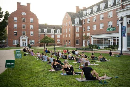 Dozens of Ohio University students practice yoga outdoors at sunrise